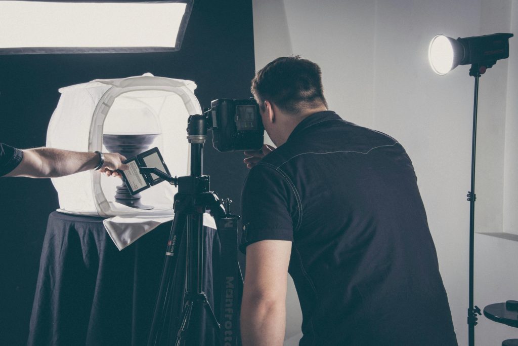 shows a photographer taking  product images of a vase in a well lit light box